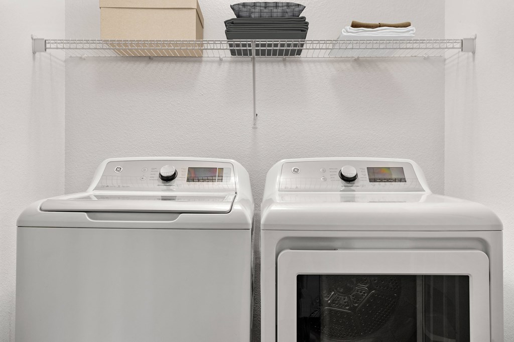 Two white front loading washing machines in a laundry room.