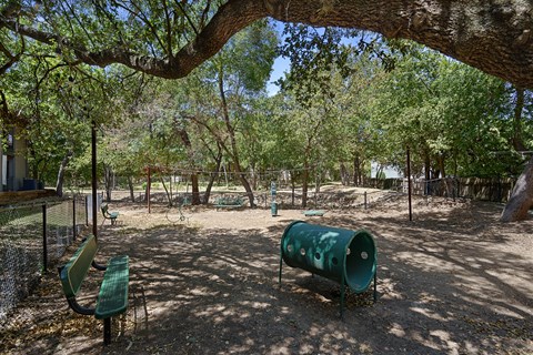 A playground with a green slide and a green barrel.