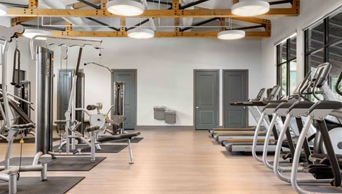 A gym with a variety of equipment including treadmills, weights, and exercise machines.