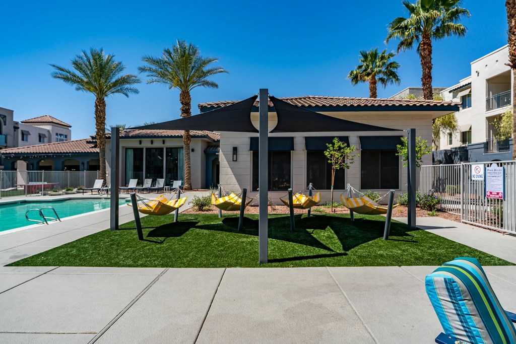 A poolside area with a black umbrella and yellow chairs.