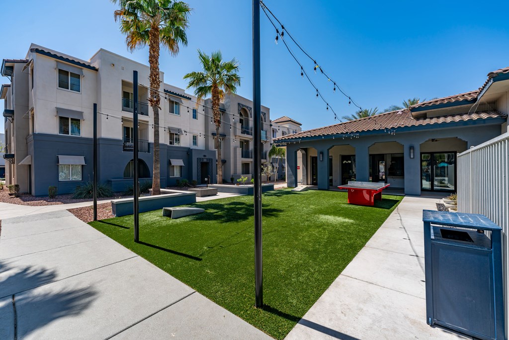 A sunny day at a residential area with apartment buildings, palm trees, and a blue trash bin.
