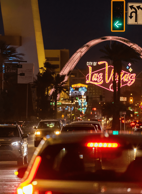 Cars are driving on a busy street at night.