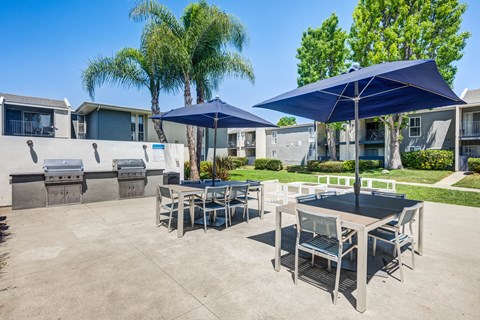 A patio with a table and chairs under umbrellas.