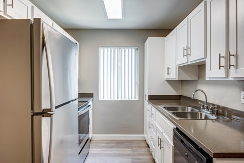A kitchen with a white refrigerator and cabinets.