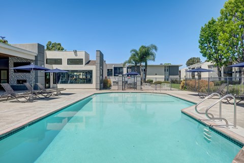 A swimming pool surrounded by a fence and chairs.