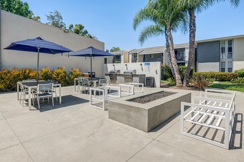 A patio with a table, chairs, and umbrellas.