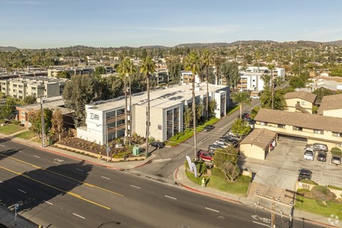 A street view of a residential area with apartment buildings and parked cars.