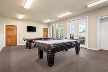 A room with a pool table and a television mounted on the wall.