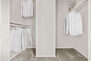 A white shirt is hanging on a hanger in a white closet.