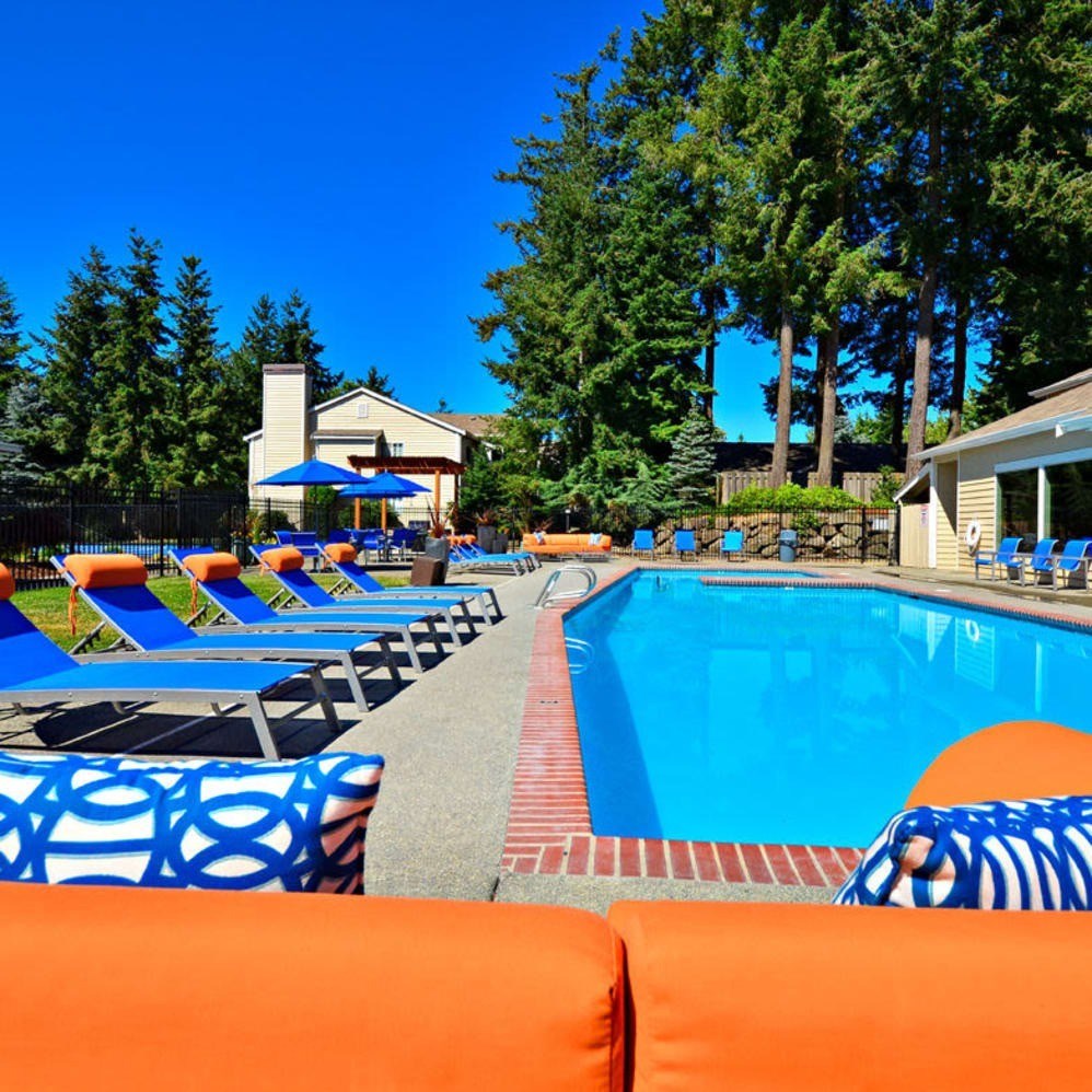 A pool area with blue chairs and a red brick border.