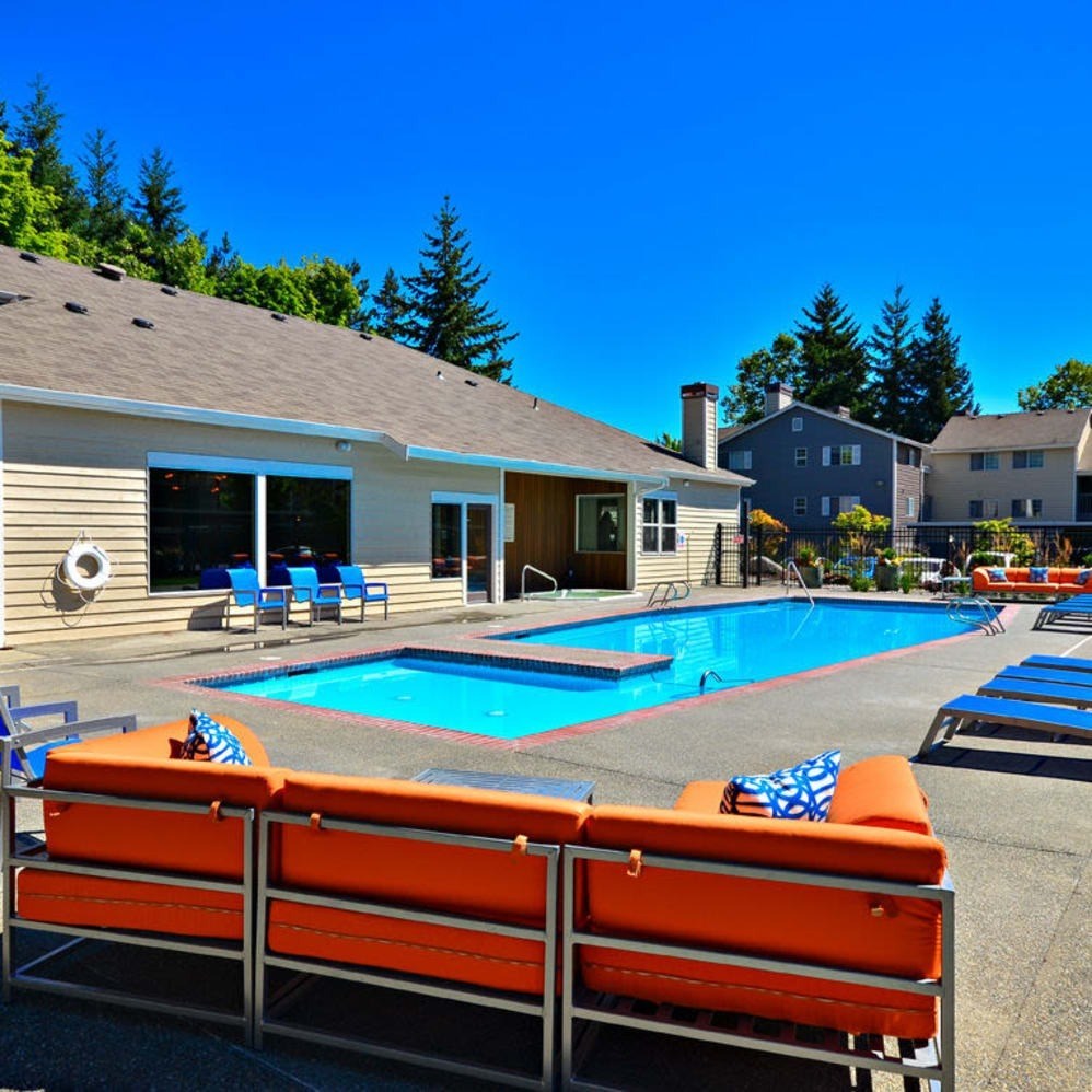 A poolside area with orange sun loungers and a clear blue sky.