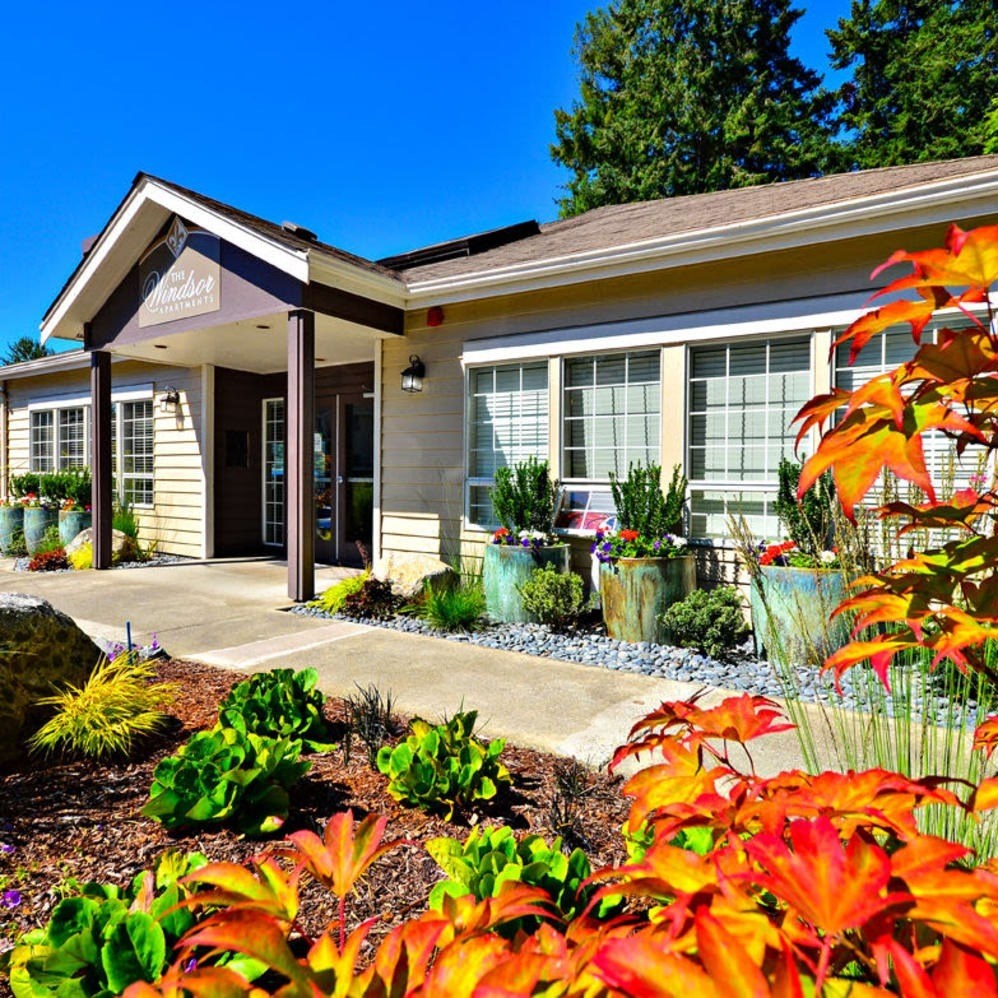 A small building with a porch and a garden in front.