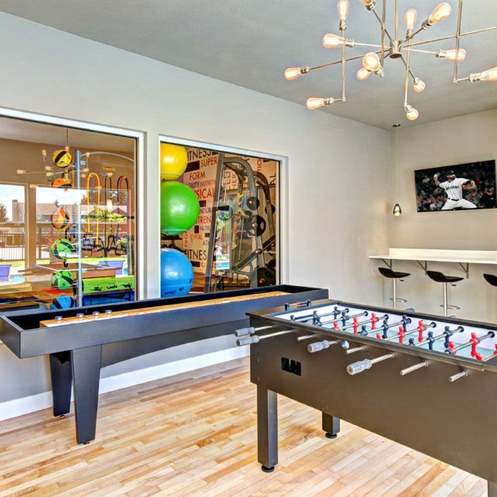 A room with a foosball table and a pool table.