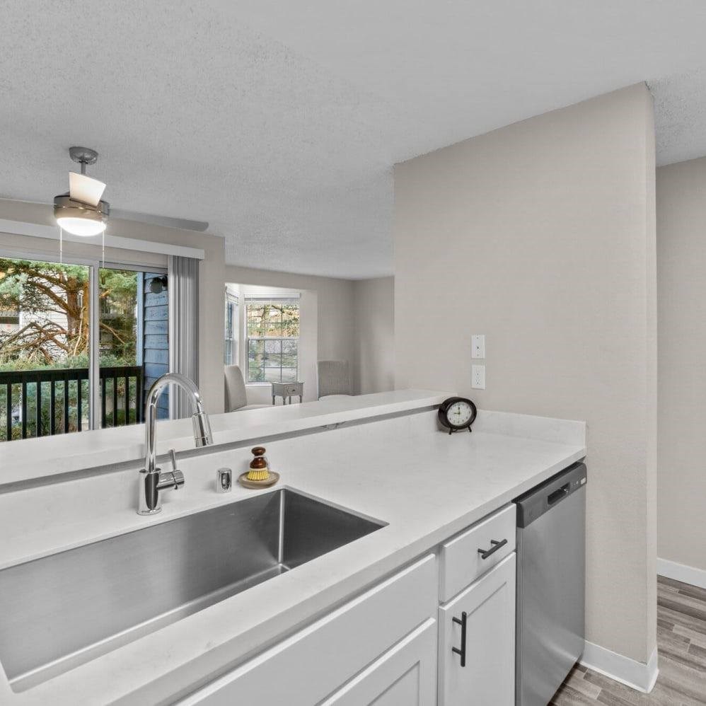 A modern kitchen with a stainless steel sink and white cabinets.