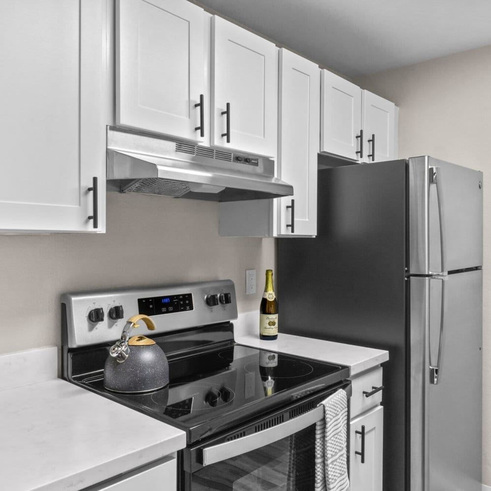 A black fridge sits next to a white counter in a kitchen.