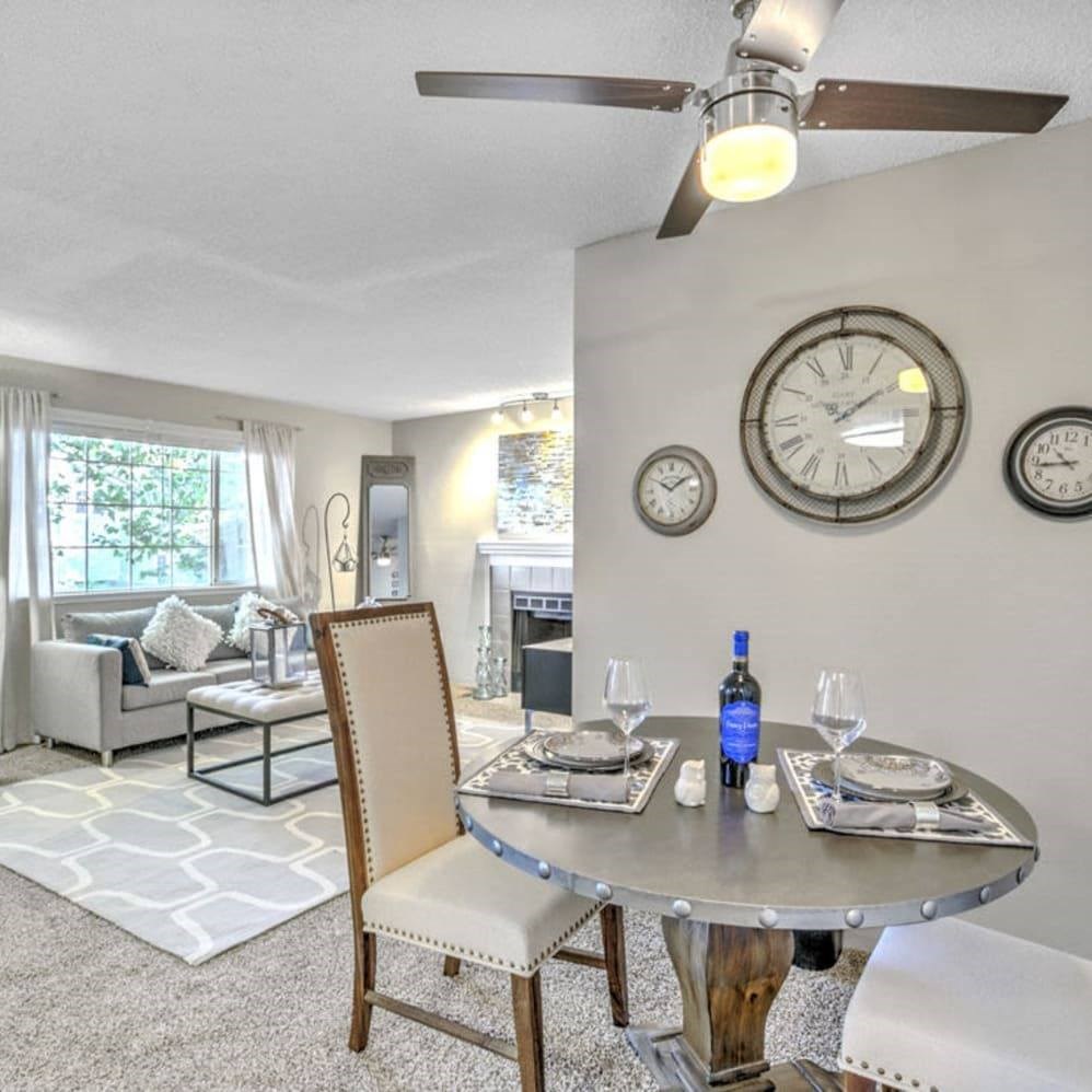 A dining room with a table set for two and a ceiling fan.