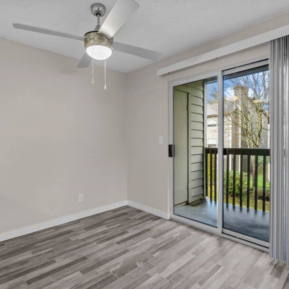 A room with a ceiling fan and sliding glass doors.