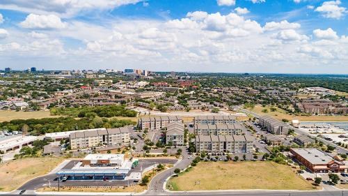 A large, modern building complex is surrounded by a parking lot and other buildings.