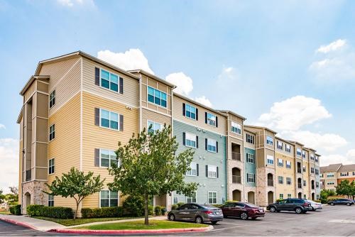 A large apartment complex with multiple buildings and cars parked in the lot.
