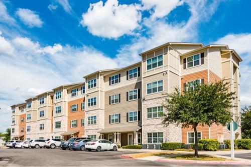 A large apartment building with a parking lot in front.