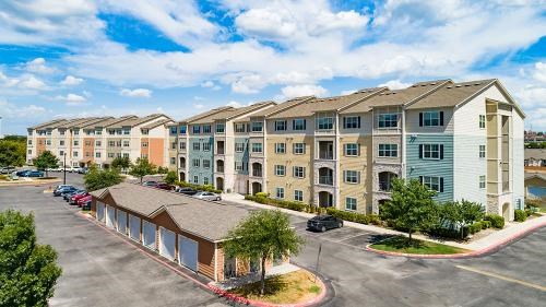 A large apartment complex with a parking lot in front.