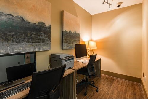 A room with a desk, two chairs, a monitor, a keyboard, a mouse, a printer, and a lamp.