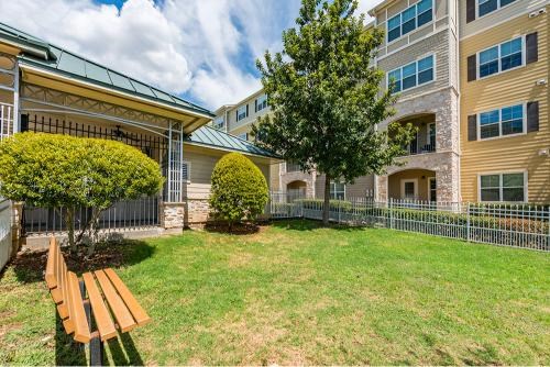 A grassy area with a bench and a tree in front of a building.
