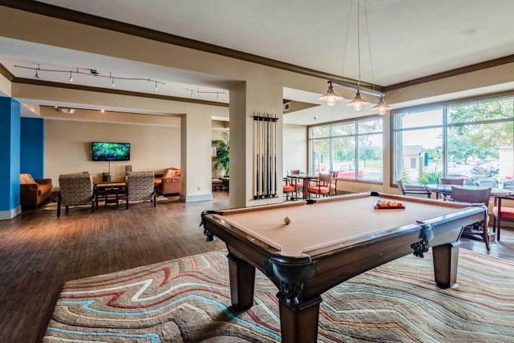 A pool table is in the middle of a room with a television and chairs.