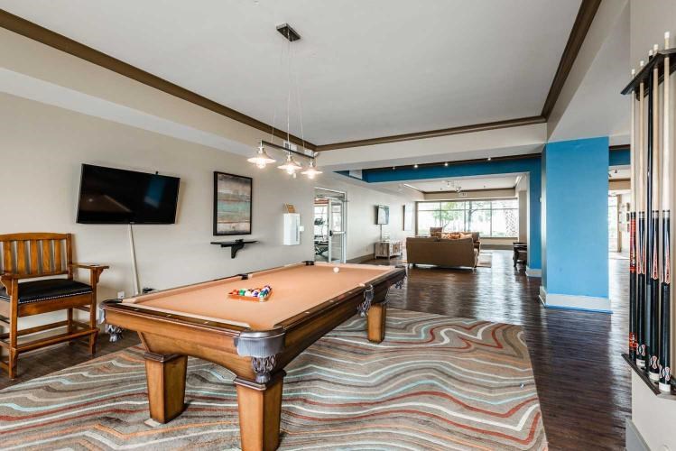A pool table is in the middle of a room with a chair and a television.