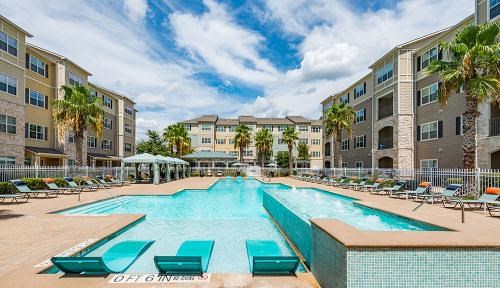 A large swimming pool surrounded by lounge chairs and palm trees.