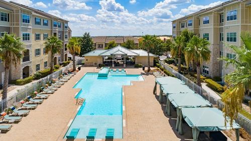 A large swimming pool surrounded by sun loungers and umbrellas in a residential area.