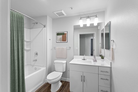A white bathroom with a toilet, sink, and shower.