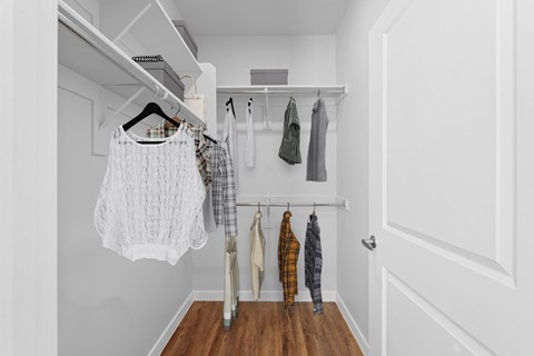 Clothes hanging on a rack in a white room.