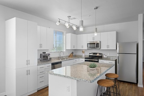 A kitchen with white cabinets and a granite countertop.