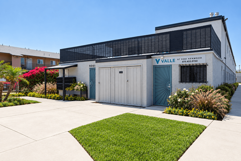 A building with a sign that says "VALLE" is surrounded by a green lawn.