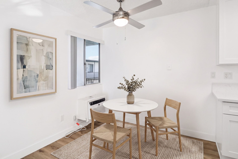 A dining room with a white table and chairs.