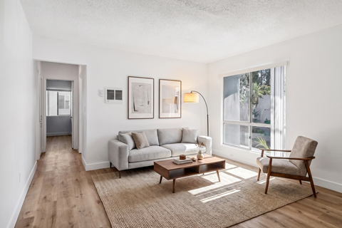 A living room with a grey couch, a brown coffee table, and a chair.