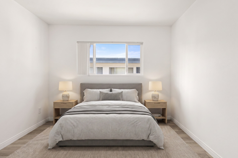 A bedroom with a large bed and two lamps.