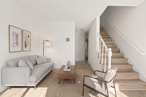 A living room with a couch, chair, and stairs.