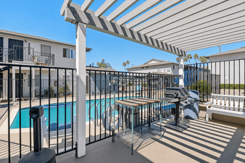A pool area with a white pergola and black fence.