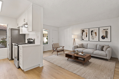 A modern kitchen with a refrigerator, a dining table, and a couch.