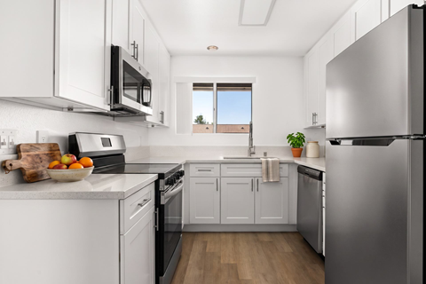 A kitchen with white cabinets and a stainless steel refrigerator.