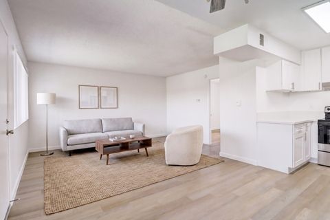 A living room with a grey couch, a white chair, and a wooden coffee table.