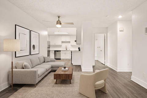 A modern living room with a grey sofa, a wooden coffee table, and a beige armchair.