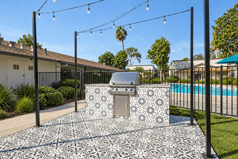 A backyard with a pool and a BBQ grill.