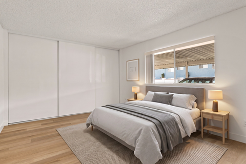 A bedroom with a bed, nightstands, and a window.