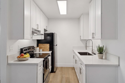 A kitchen with white cabinets and a black refrigerator.