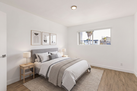 A bedroom with a large bed and a window overlooking a street.