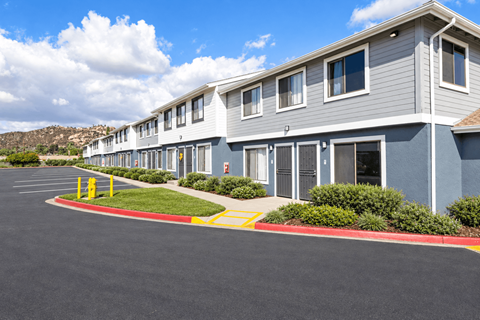 A row of grey houses with a red and yellow striped curb in front.