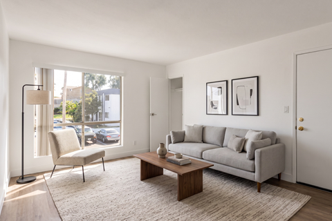 A living room with a grey couch, a chair, a coffee table, and pictures on the wall.